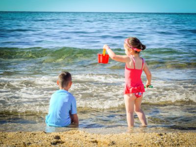 Två barn som leker vid en strand.