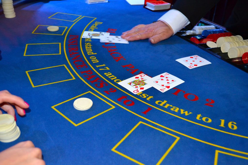 Bilden visar ett bord på ett casino. Två personer har satsat pengar och visat sina kort.