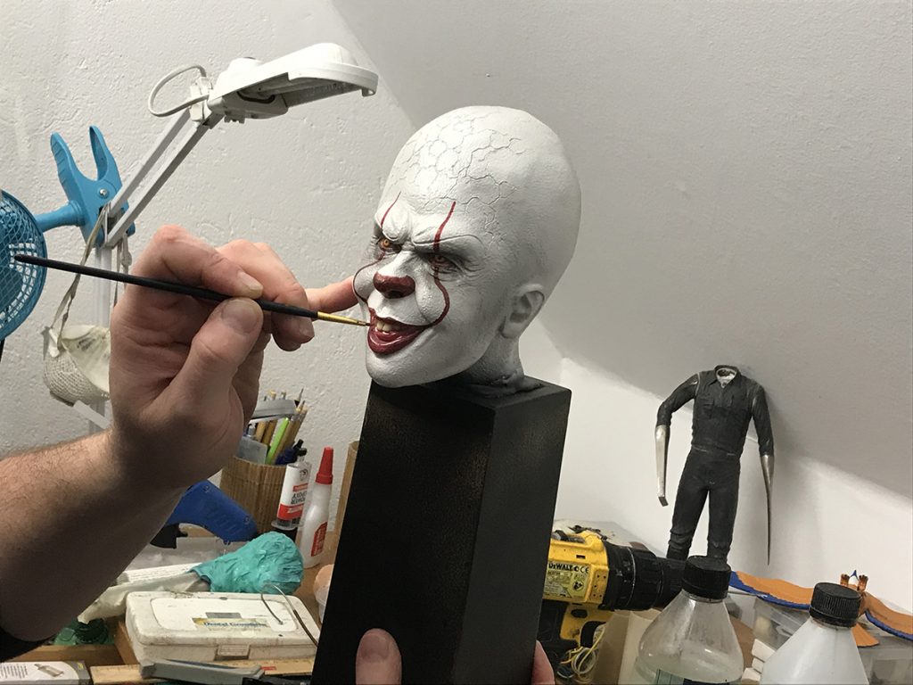 Björn målar detaljer på ett vitt huvud med röda läppar.