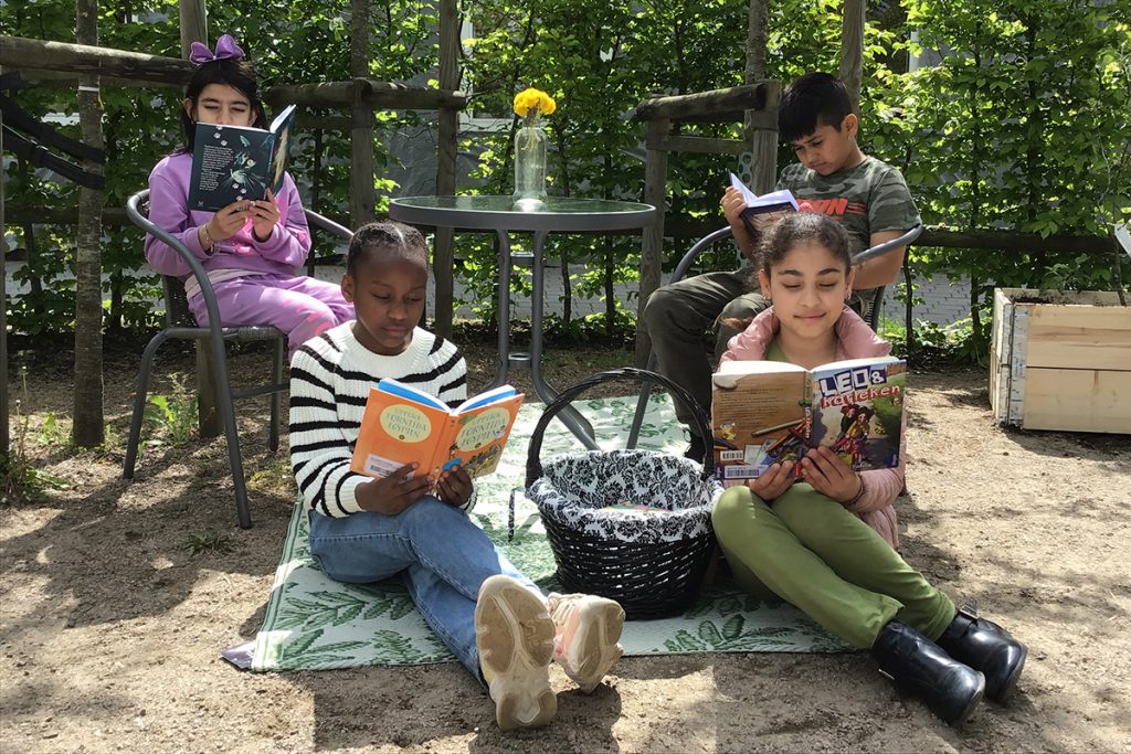 Elever som läser på en filt och på caféstolar