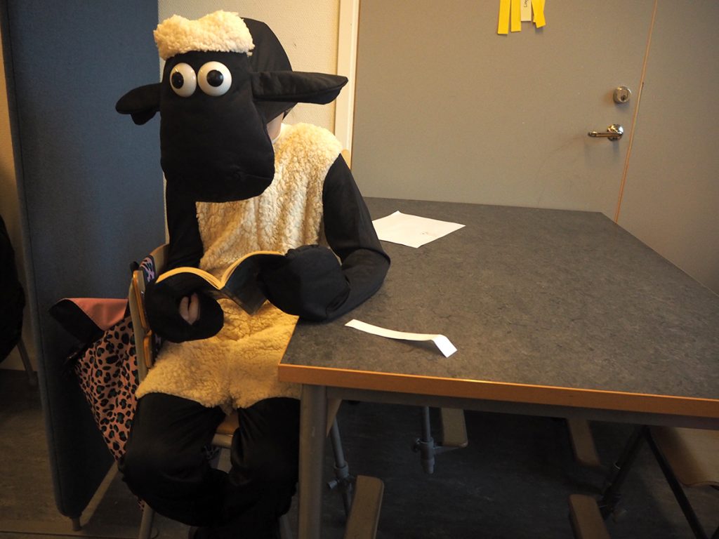 Fåret Shaun sitter och läser.